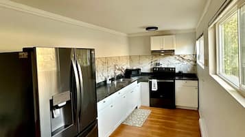 A modern kitchen with a stainless steel refrigerator, white cabinets, and a wooden floor.