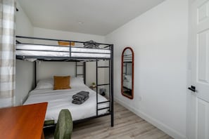 A bunk bed room with a wooden table, a green chair, and a mirror on the wall.