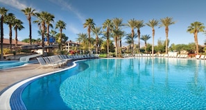 A large, curved swimming pool with lounge chairs and palm trees around it. - Perfect Coachella accommodation - amazing value sleeps 4 (Palm Desert)