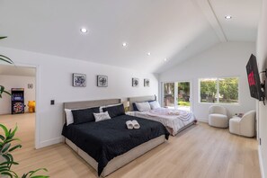 Quarto moderno com duas camas, uma televisão de tela plana e uma janela grande.