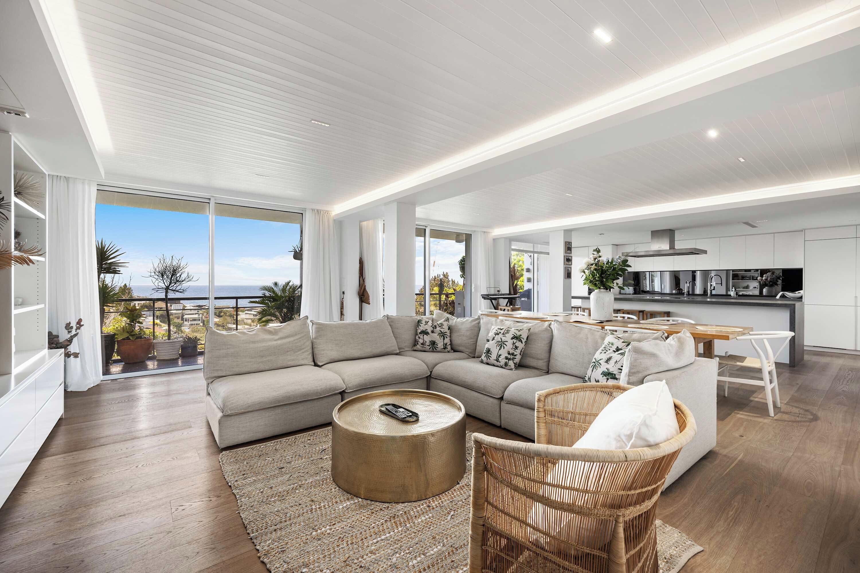 A modern living room with a sectional sofa, a round coffee table, and a wicker chair.