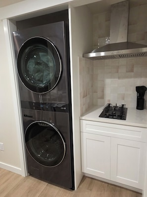 A compact kitchen with a built-in washer and dryer, a gas stove, and white cabinetry.