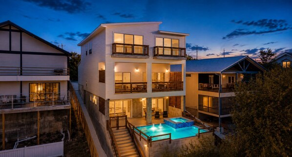 Una casa de varios pisos con piscina, balcones y una escalera que lleva a los niveles superiores.