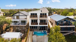 A multi-story residential building with a swimming pool, balconies, and a view of the surrounding landscape. - Lakeside Lakehouse & Bunkbed Cabin, Pool, Dock, Gameroom/All king beds &own bath (Spicewood)