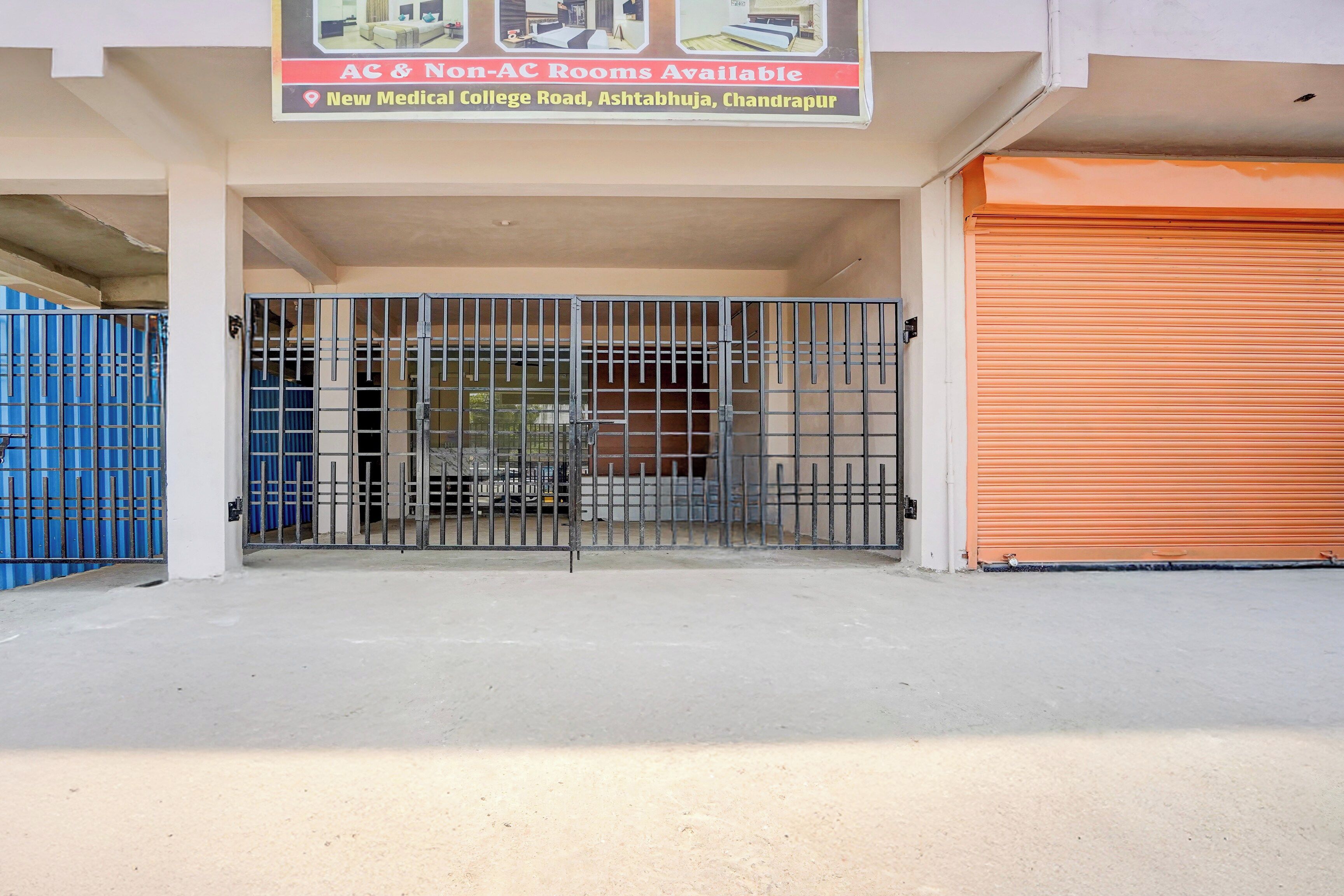 A gated entrance to a building with a sign indicating AC & Non-AC rooms available.