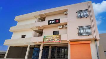 A multi-story hotel with balconies, air conditioning units, and a sign advertising AC & Non-AC rooms.