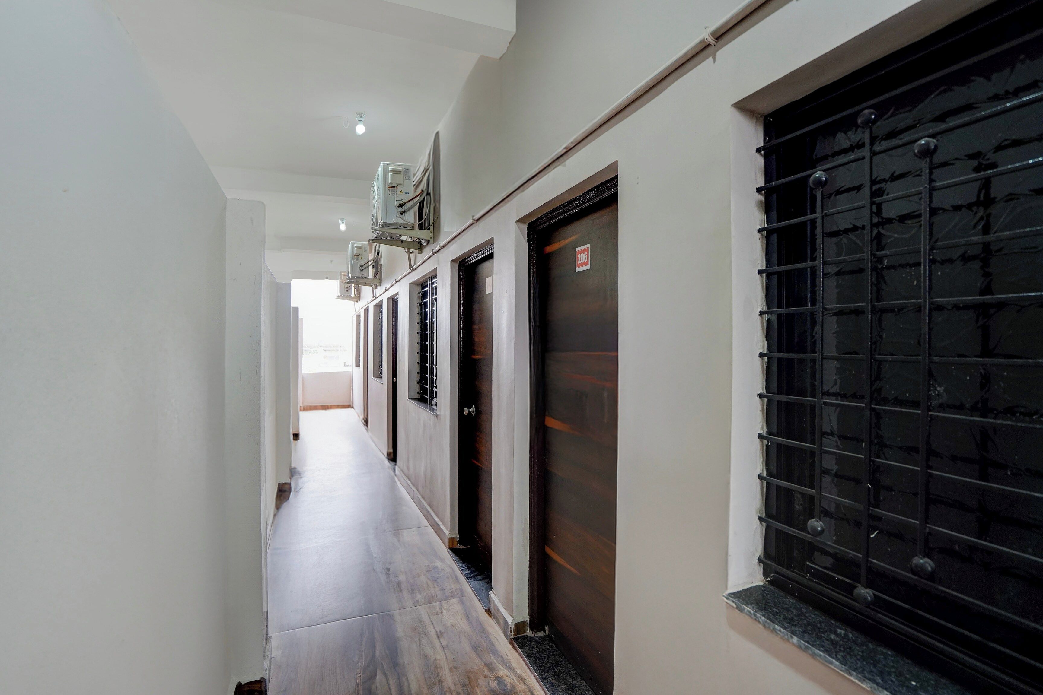 A corridor with a tiled floor, a door with a number plate, and a window with a metal grille.