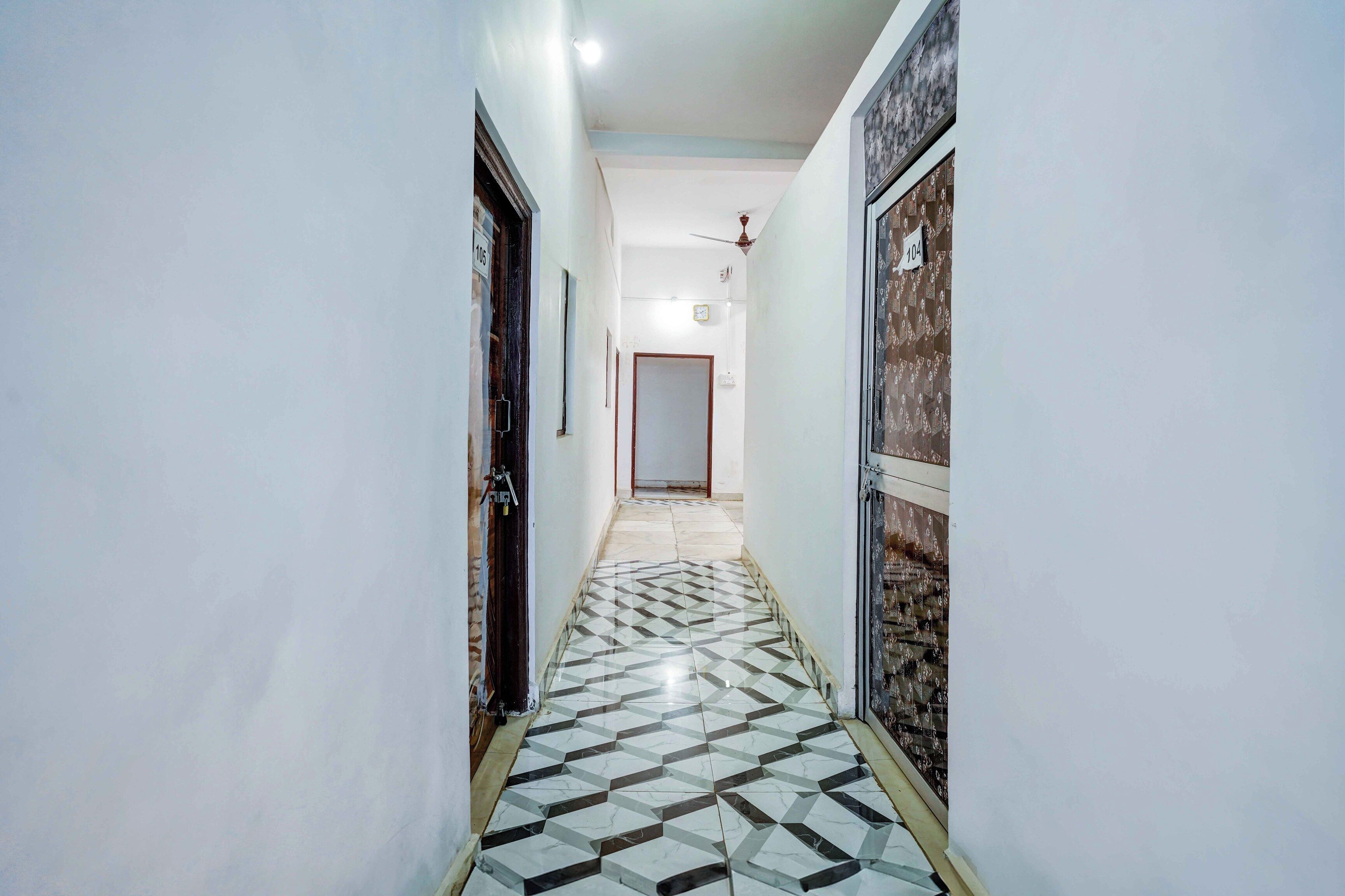 Un pasillo con piso de diseño geométrico, paredes blancas y puertas numeradas 105 y 104.