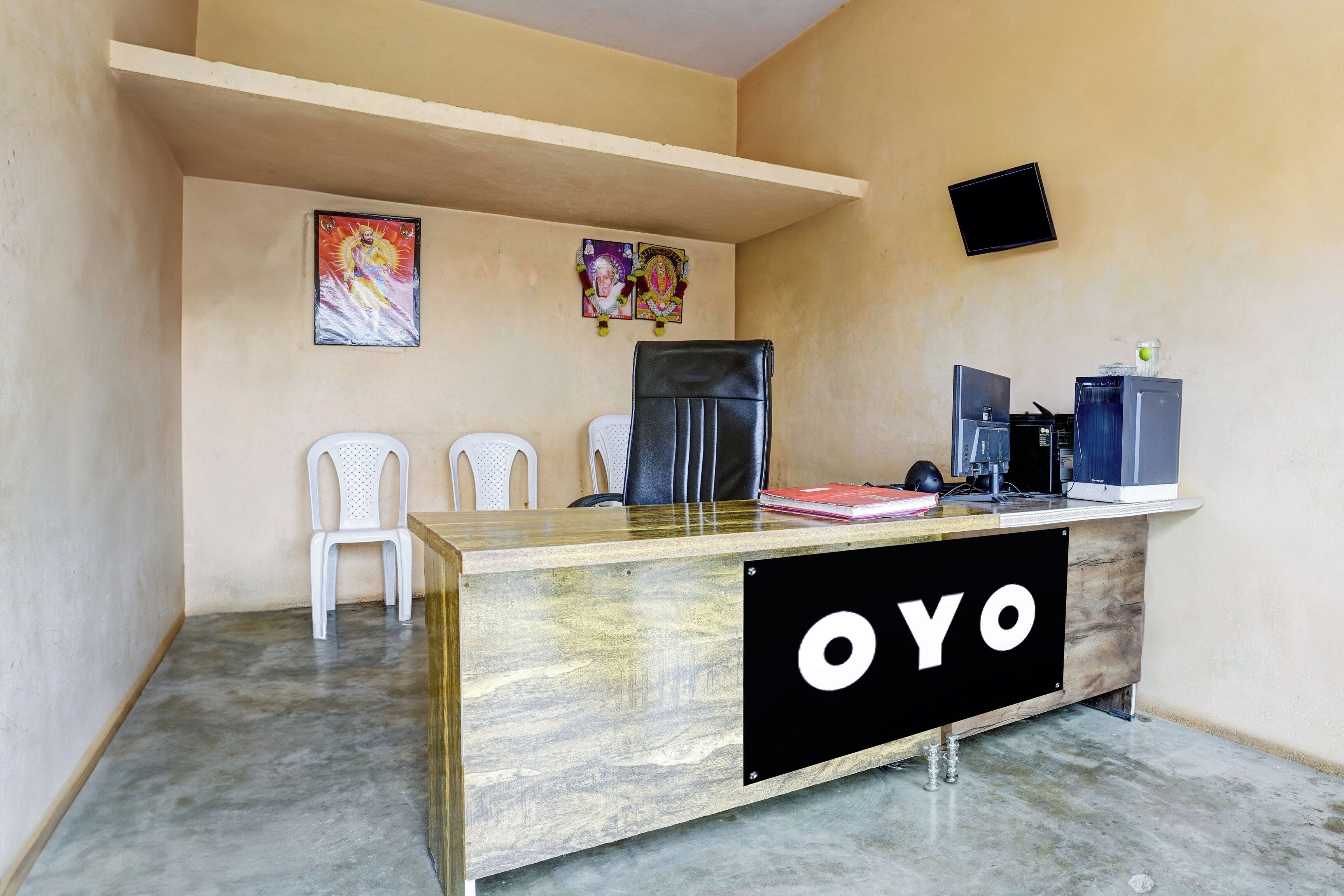 A reception desk with a 'YO' sign, two white chairs, a refrigerator, and a computer setup.