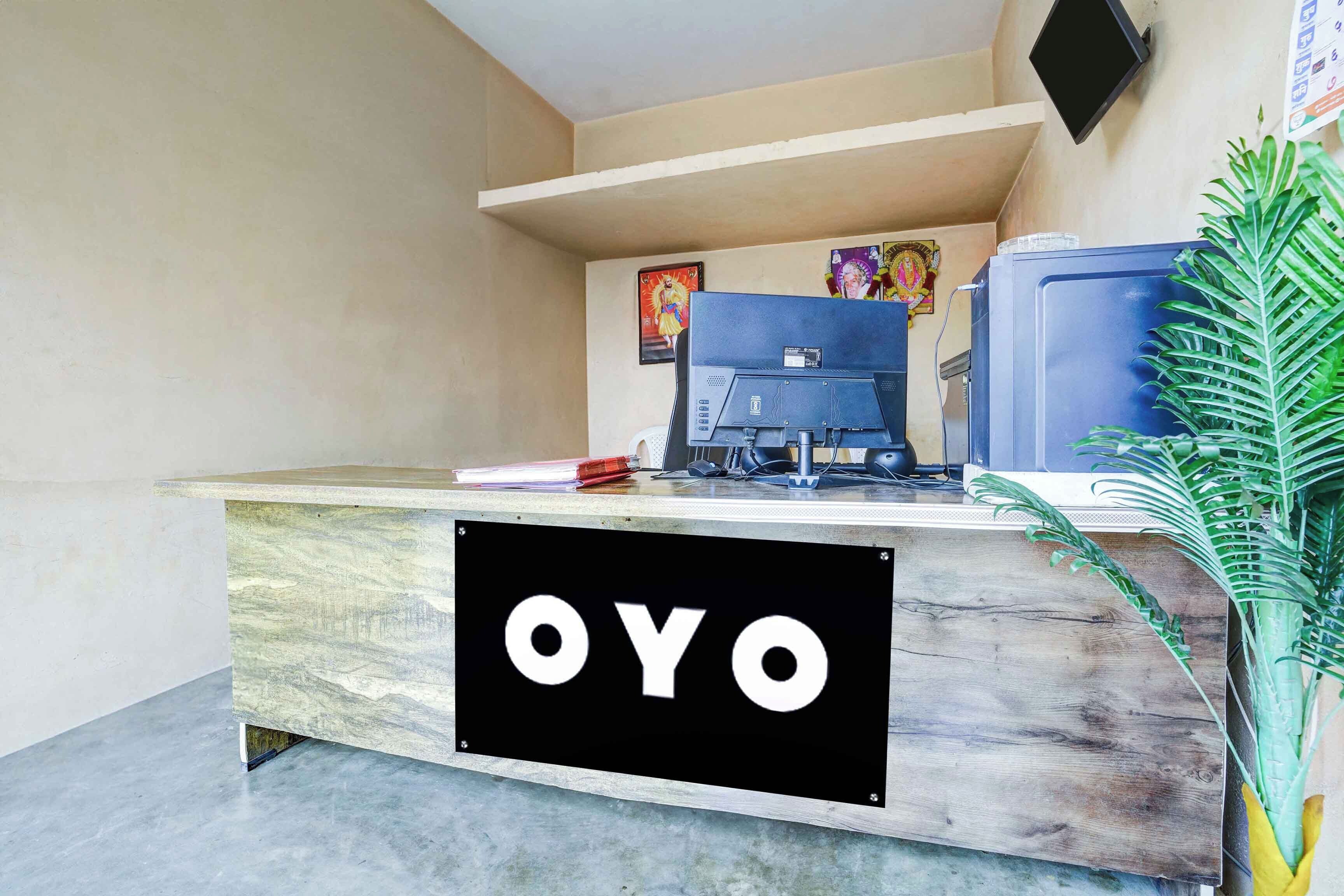 Una mesa de recepción con un cartel que dice 'OYO' y un monitor de computadora.