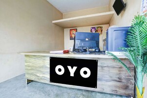 Una mesa de recepción con un cartel que dice 'OYO' y un monitor de computadora.