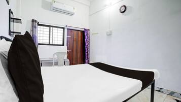 A room with a bed, a window with a view, an air conditioning unit, and a clock on the wall.