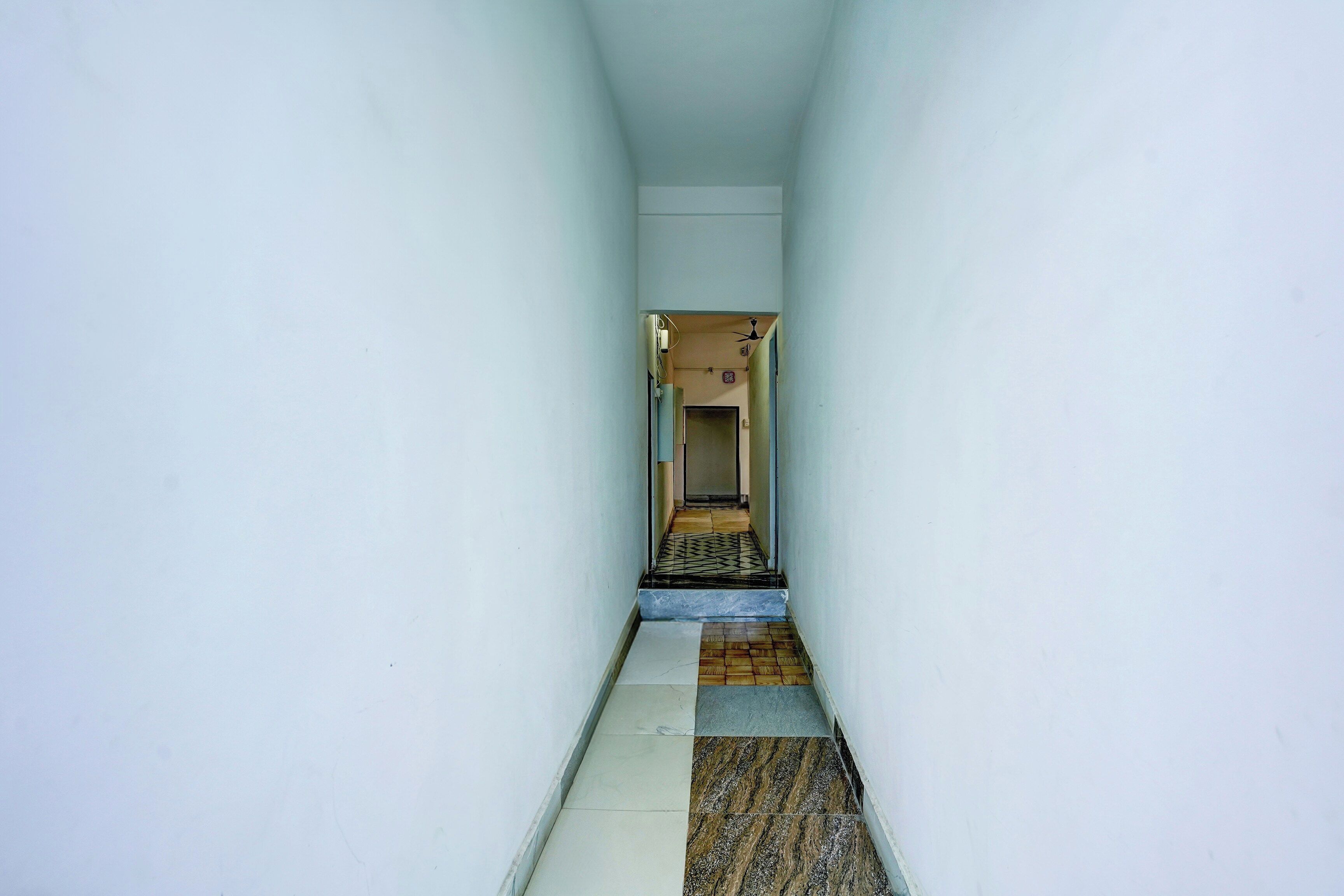 A narrow hallway with a tiled floor leading to a door at the end.