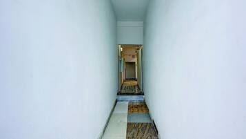 A narrow hallway with a tiled floor leading to a door at the end.