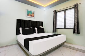 Un dormitorio con cama, cabecera, ventana con cortinas e imagen colgada en la pared.