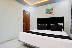 Una habitación de hotel con una cama, una puerta, un interruptor de luz y una lámpara fijada a la pared.