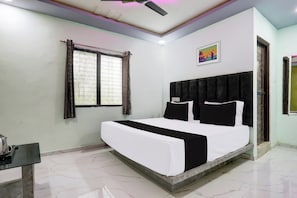 Habitación de hotel con una cama, una ventana con cortinas, un ventilador de techo y un cuadro en la pared.
