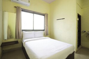 Habitación de hotel con cama, ventana con cortinas, aire acondicionado y una puerta.