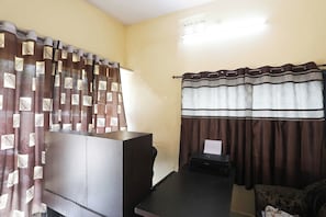 Una habitación con cama, escritorio, impresora y cortinas.