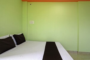 A room with a bed, a power outlet, and a light switch on the wall.