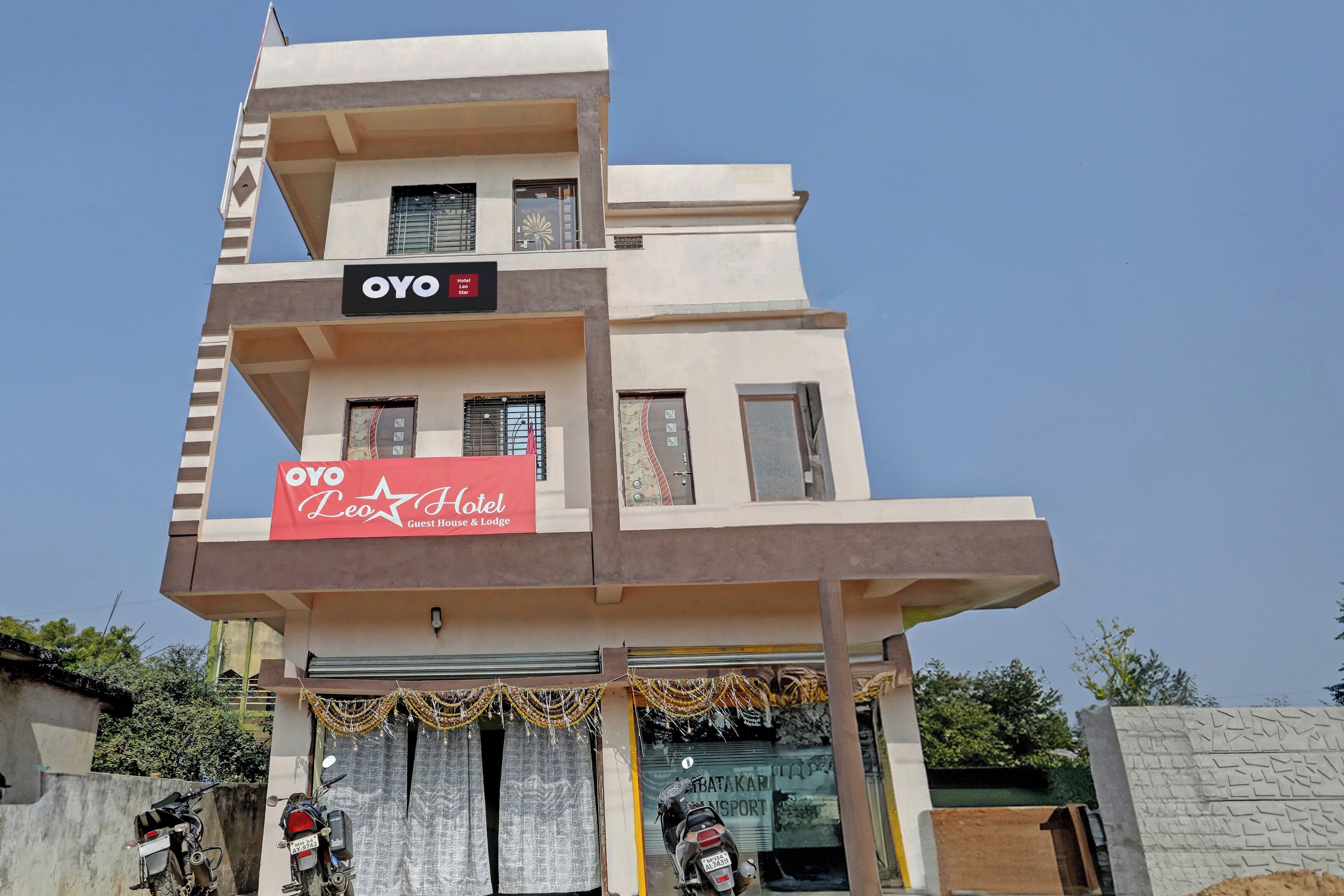 Un edificio de varios pisos con un letrero que indica 'OYO Leo Hotel', mostrando un alojamiento de huéspedes y una posada.