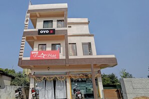 Un edificio de varios pisos con un letrero que indica 'OYO Leo Hotel', mostrando un alojamiento de huéspedes y una posada.