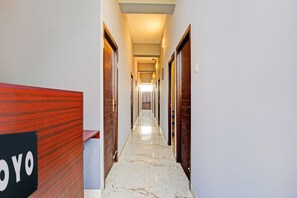 A hotel hallway with wooden doors, a marble floor, and a sign with 'YOYO' on it.