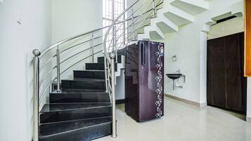 A staircase with metal railings and a black refrigerator with decorative stickers.