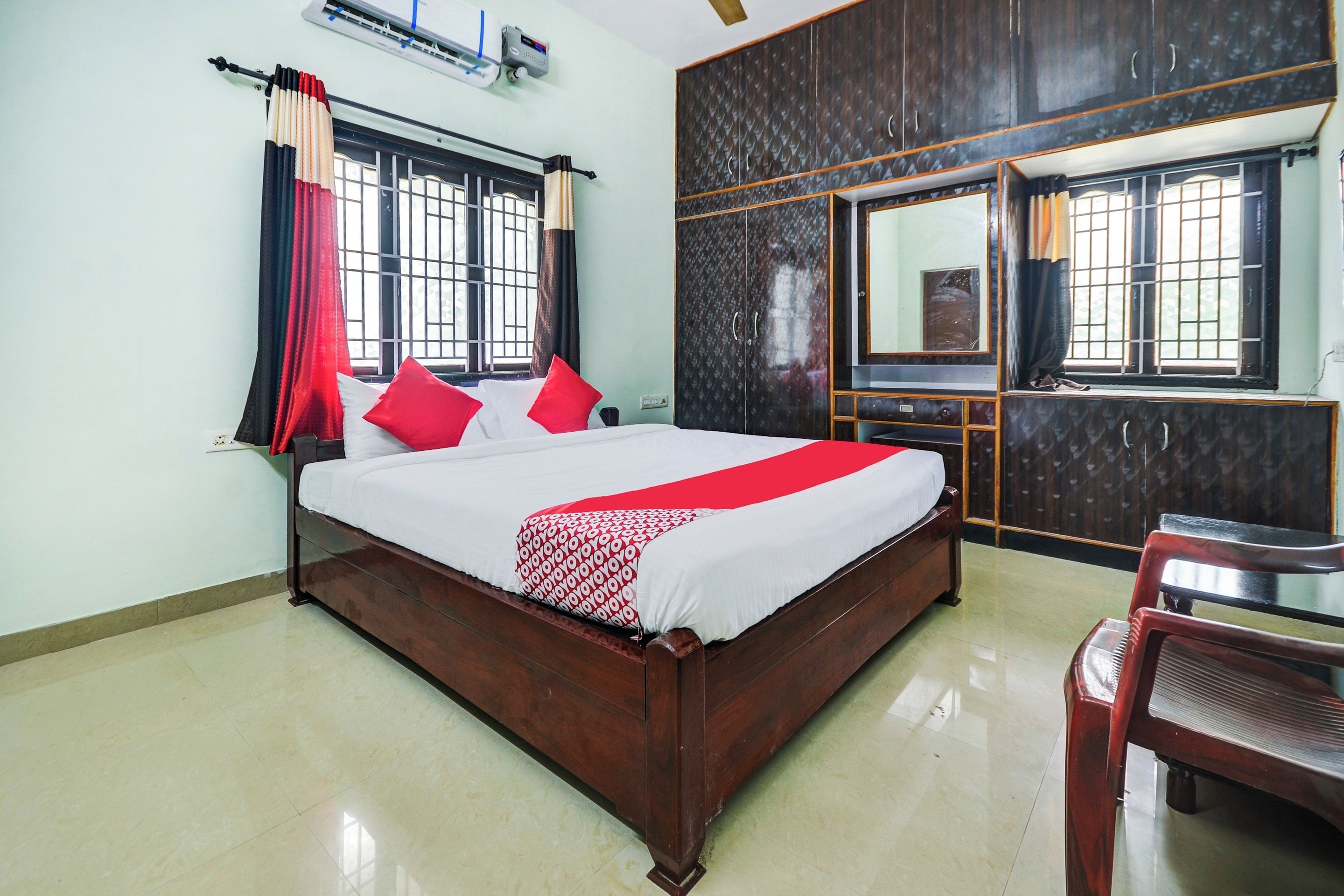 A hotel room with a large bed, a desk, a chair, and a mirror.