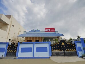 A residential building with a blue and white facade, a sign indicating it is an Aruthraaa Residency, and a gated entrance with decorative black and gold gates. - Hotel O Aruthraa Residency (Coimbatore)