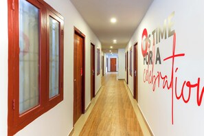 A hotel corridor with wooden doors and a wall with a motivational quote. - Collection O Marhaba Govindapuram (Kozhikode)