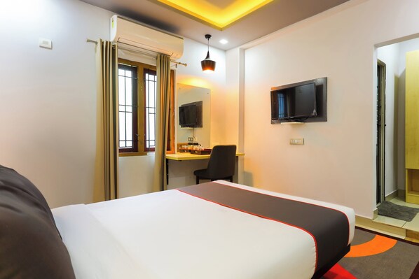 A hotel room with a bed, a desk, a chair, a television, and a window with curtains. - Collection O Marhaba Govindapuram (Kozhikode)