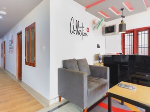 A hotel lobby with a grey sofa, a wooden table, and a wall with a 'Collection' sign. - Collection O Marhaba Govindapuram (Kozhikode)