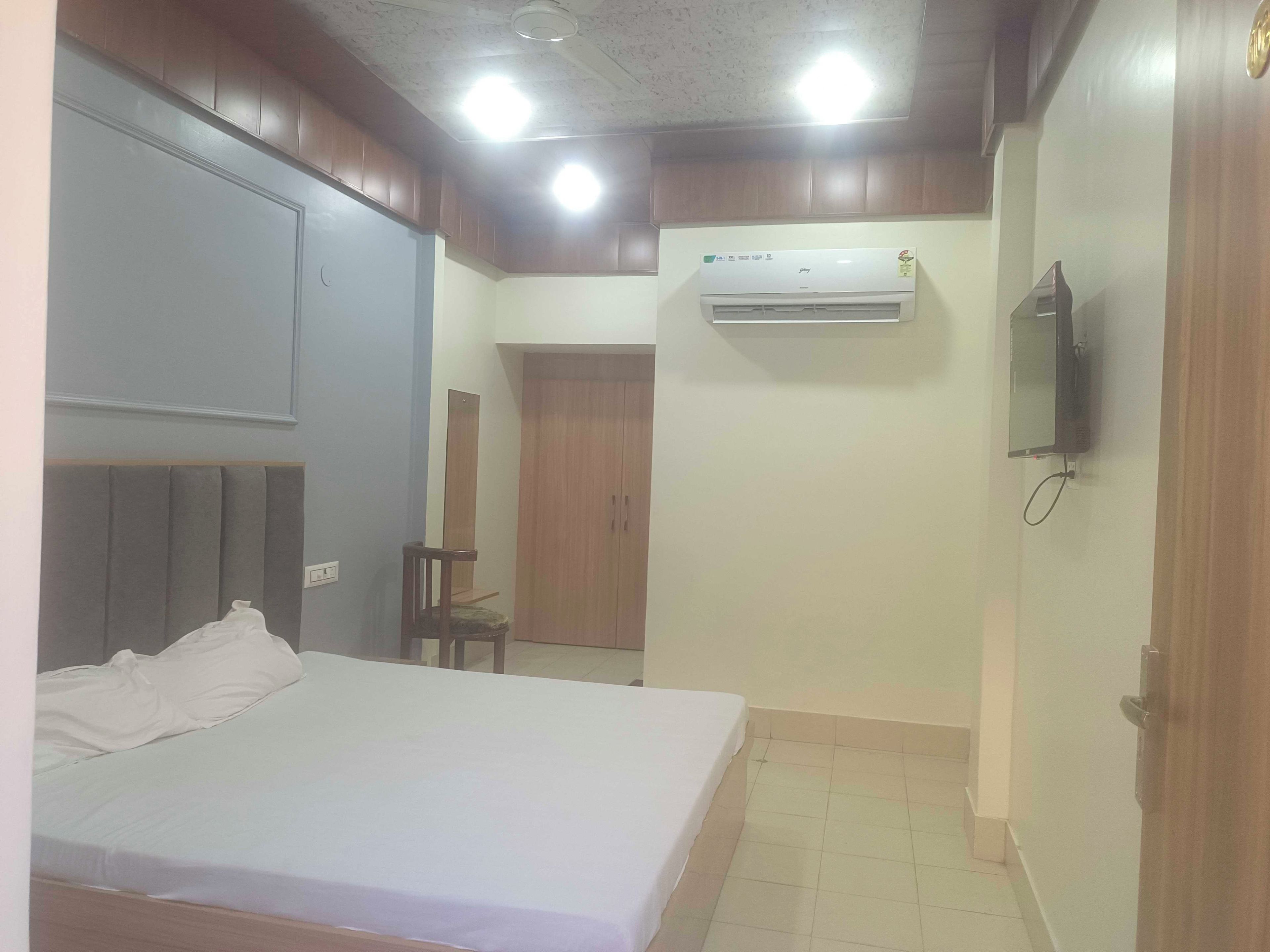 Un dormitorio con cama, armario, aire acondicionado, televisor y espejo.
