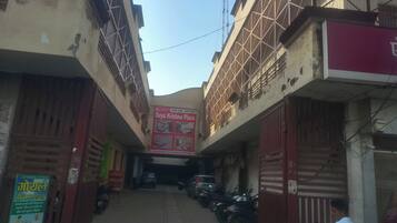 Un estrecho callejón flanqueado por edificios, un letrero que dice 'Daya Krishna Plaza' y motocicletas estacionadas.