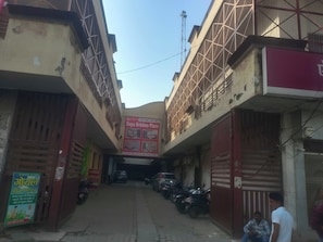 A narrow alleyway with buildings on either side, a sign for 'Daya Krishna Plaza,' and parked motorcycles. - Hotel O Daya krishna plaza (Chandausi)