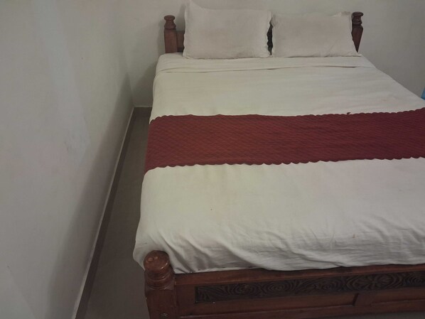 Una cama individual con cabecera de madera y ropa de cama blanca.
