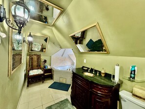 A bathroom with a bathtub, a sink, a toilet, and a vanity with a mirror. - Private Jacuzzi Penthouse in Charming 1890’s mansion (Saint Paul)