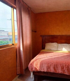 A bedroom with a single bed, a window with curtains, and a view of buildings outside. - New Listing (Ciudad Nezahualcóyotl)