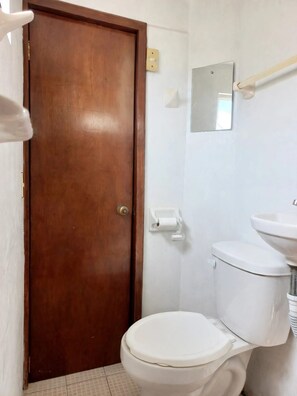 A bathroom with a wooden door, a toilet, a sink, and a mirror. - New Listing (Ciudad Nezahualcóyotl)