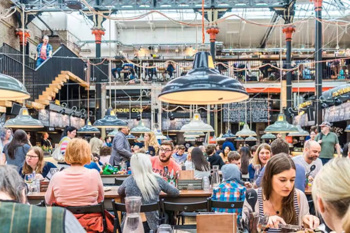A crowded indoor market with multiple levels and hanging lights.