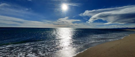 A beach with a clear sky and sunlight reflecting on the water.