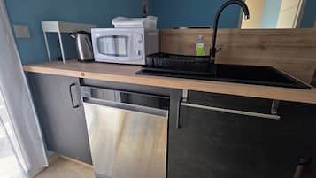 Une cuisine compacte équipée d’un four à micro-ondes, d’une bouilloire et d’un évier avec un robinet.