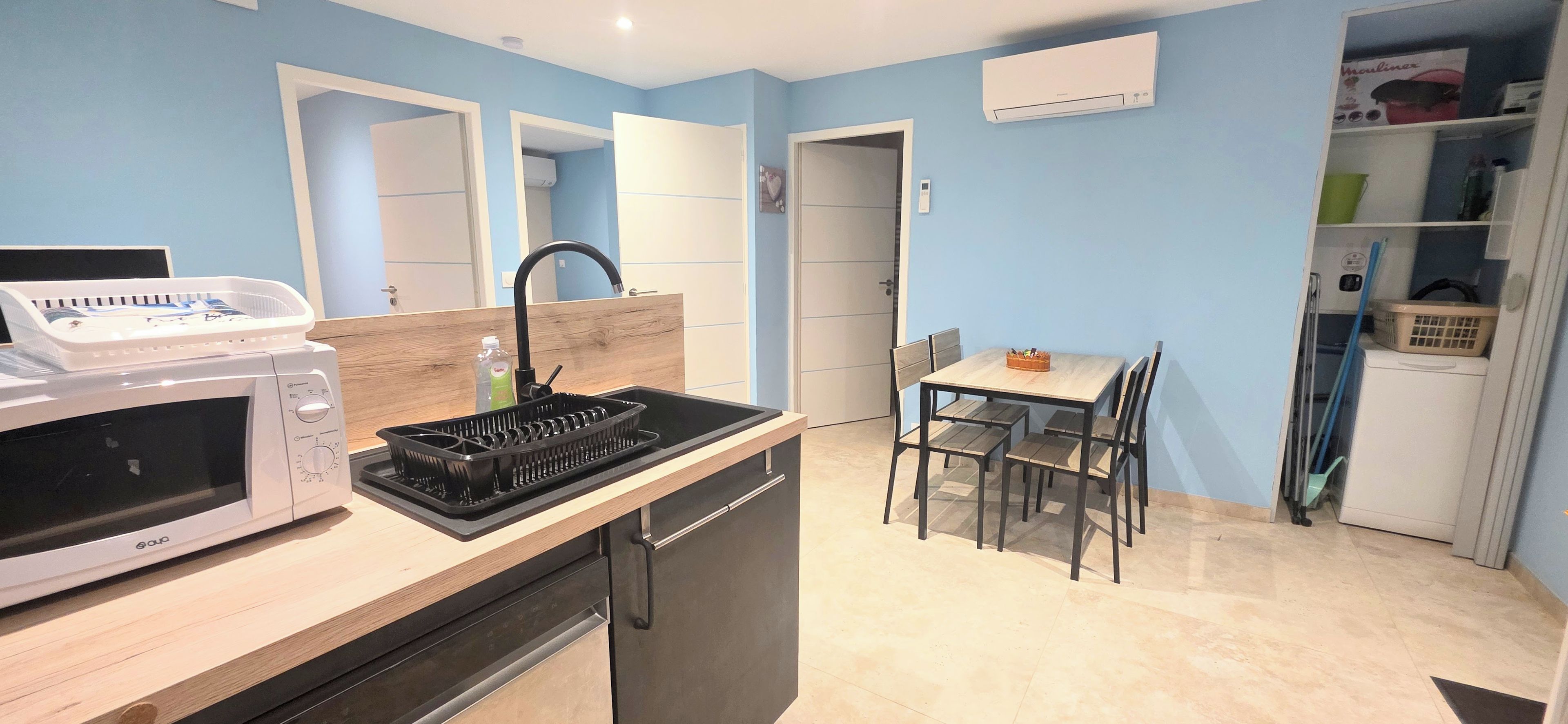 A compact kitchen with a microwave, sink, and a small dining area with a table and chairs.