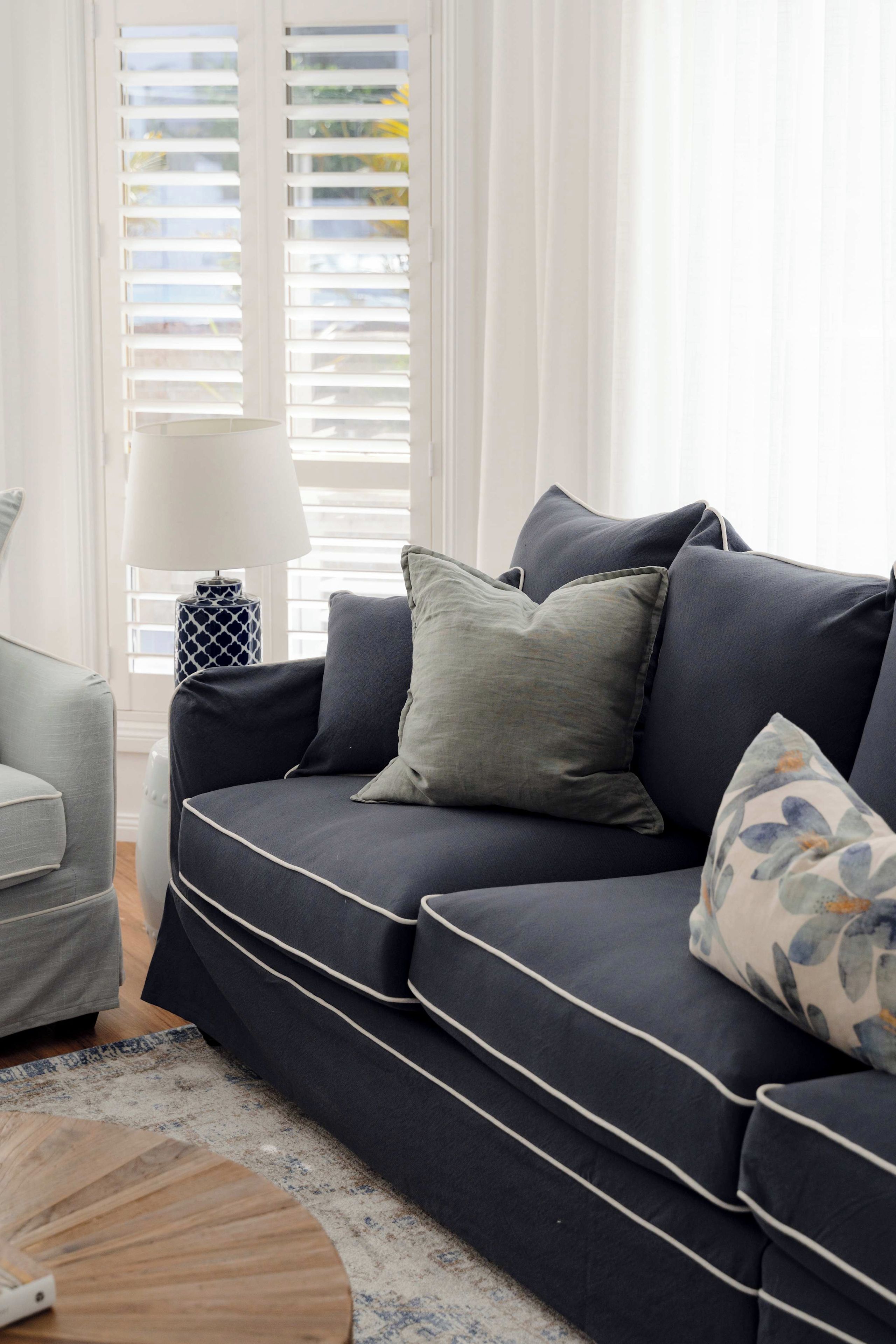 Ein modernes Wohnzimmer mit einem dunkelblauen Sofa, einem Beistelltisch und einer Lampe.