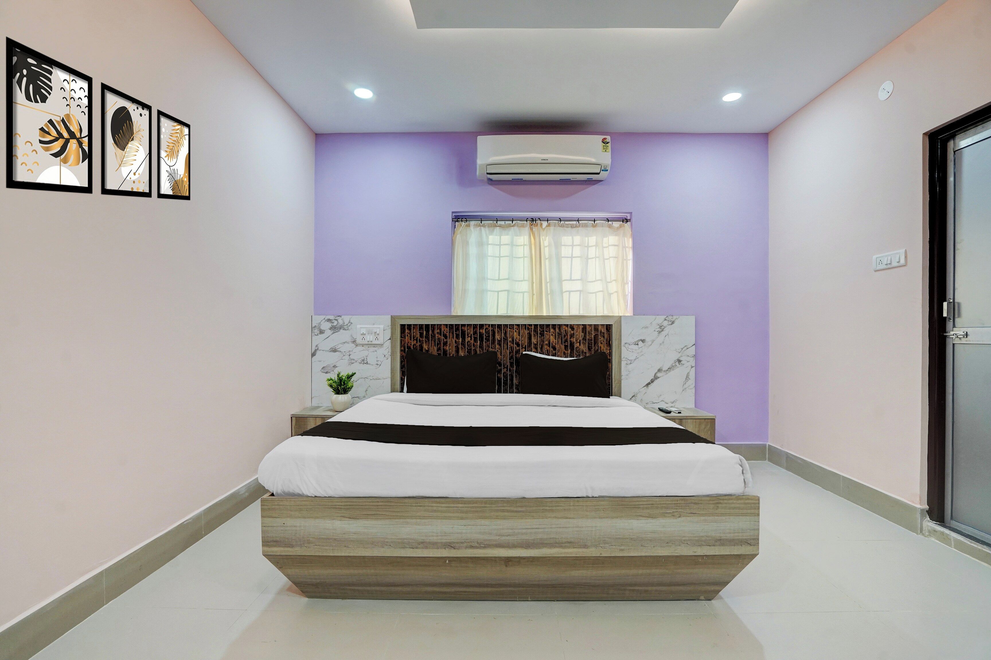 Un dormitorio moderno con cama, aire acondicionado de pared y cuadros enmarcados.
