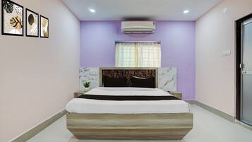 Un dormitorio moderno con cama, aire acondicionado de pared y cuadros enmarcados.