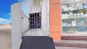 Entrada de un edificio con una puerta metálica, una rampa y un suelo de baldosas.