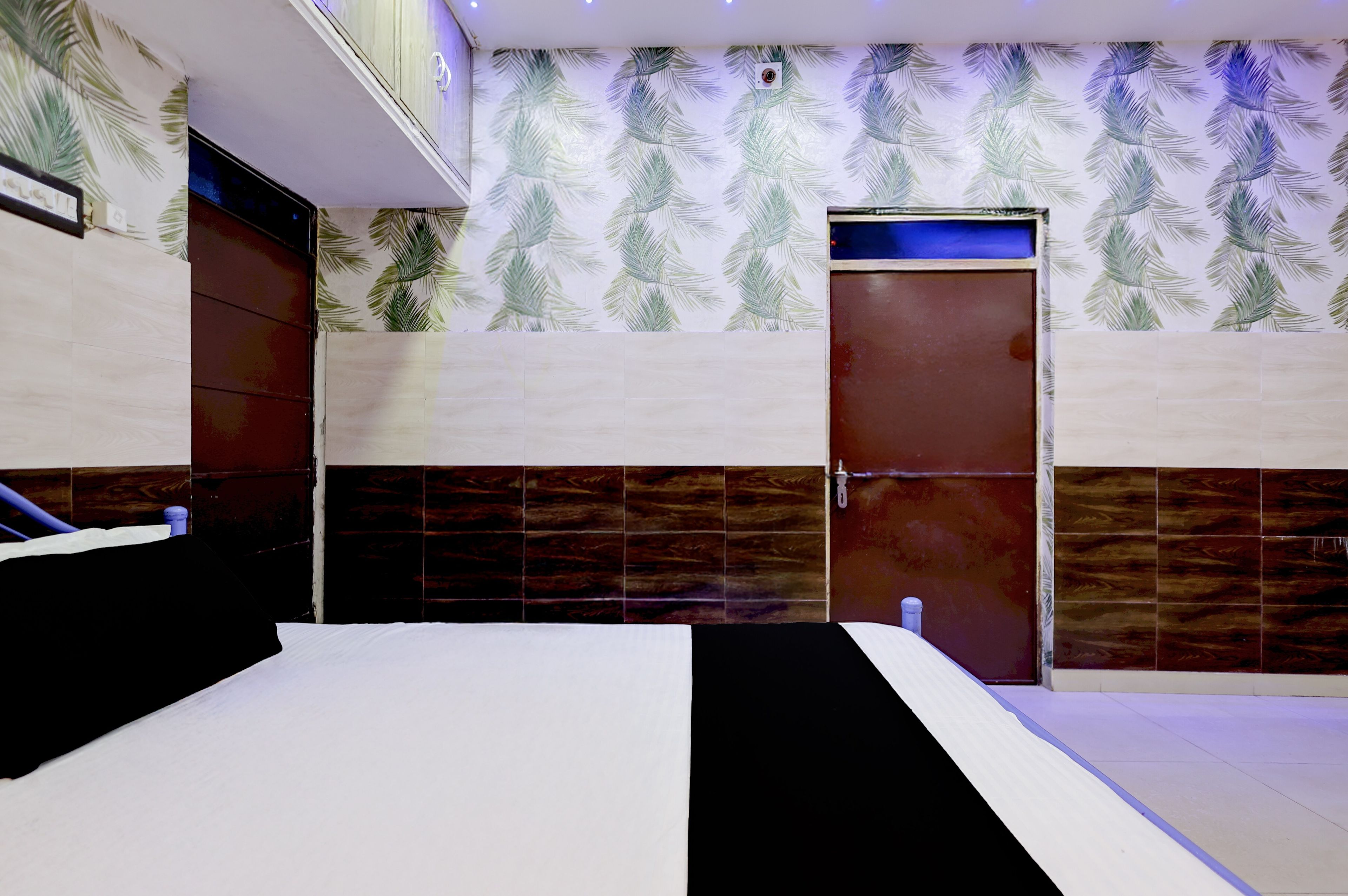Una habitación de hotel con cama, baño con espejo y una pared con diseño de hojas.