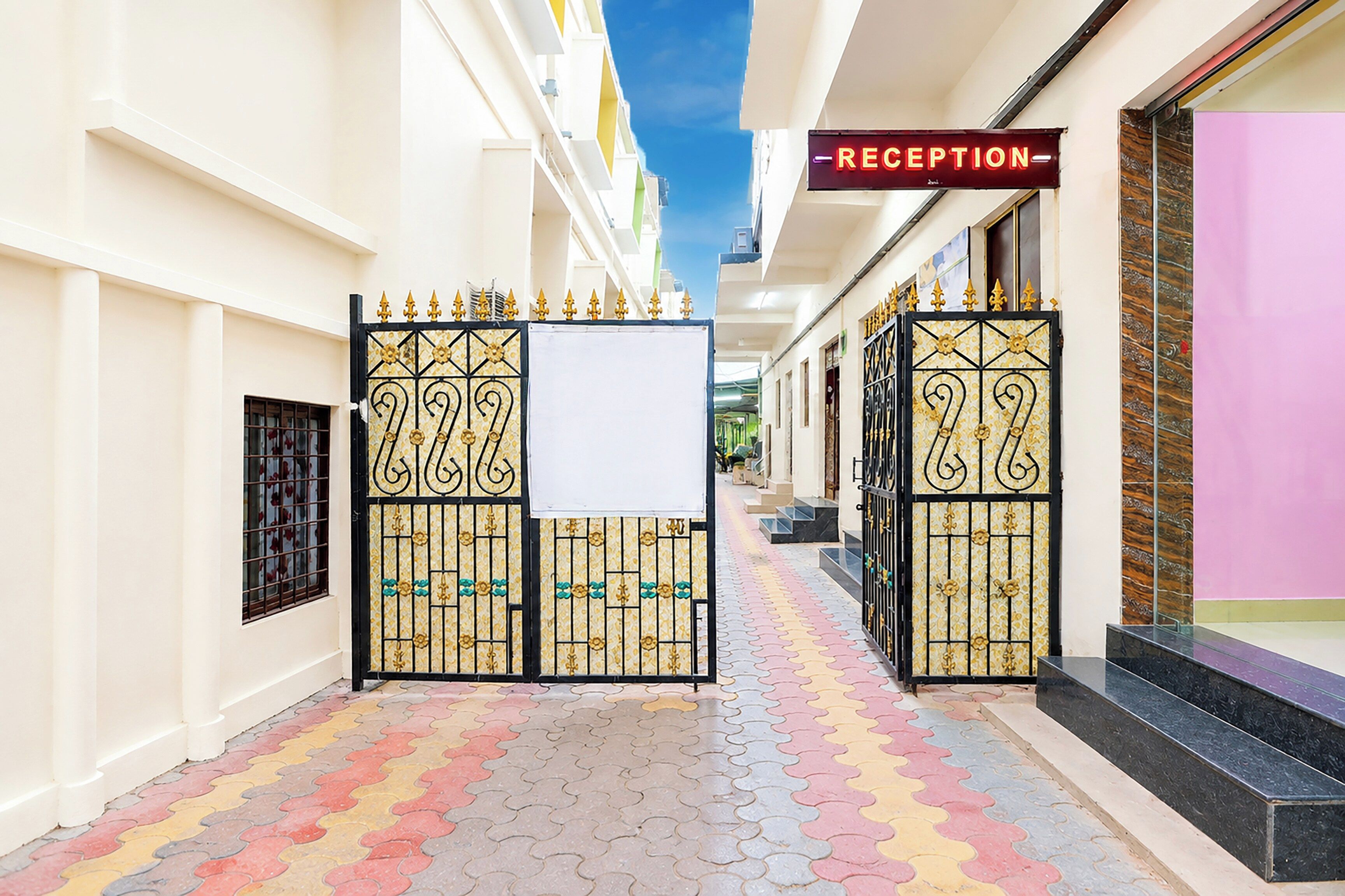 A reception area with a sign, a gated entrance, and a colorful tiled walkway.